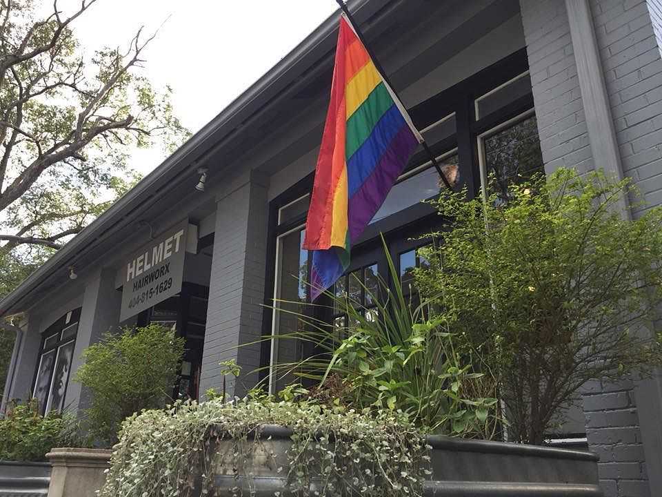 Rainbow flag hanging outside a building with greenery.